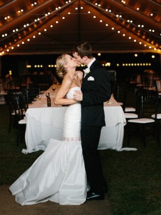 bride and groom kissing under wedding tent