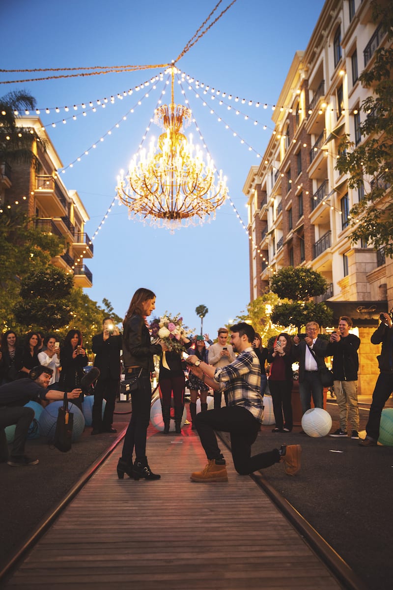 American at the Brand man down on one knee under chandelier 