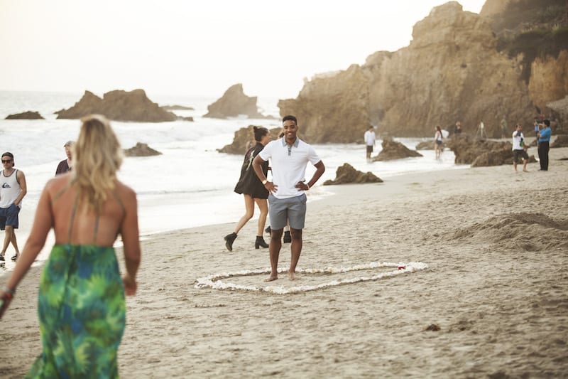 heart made of flower petals and candles and seashells on beach