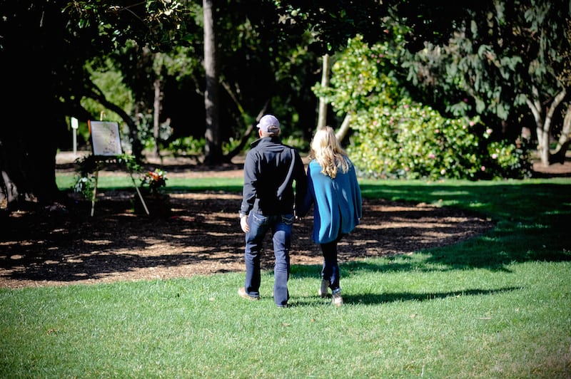 couple walking towards marriage proposal under tree