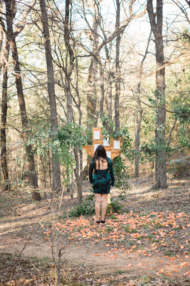 girl reading notes on sign in wooded area