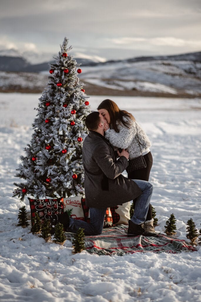 man and woman kissing at christmas marriage proposal in utah