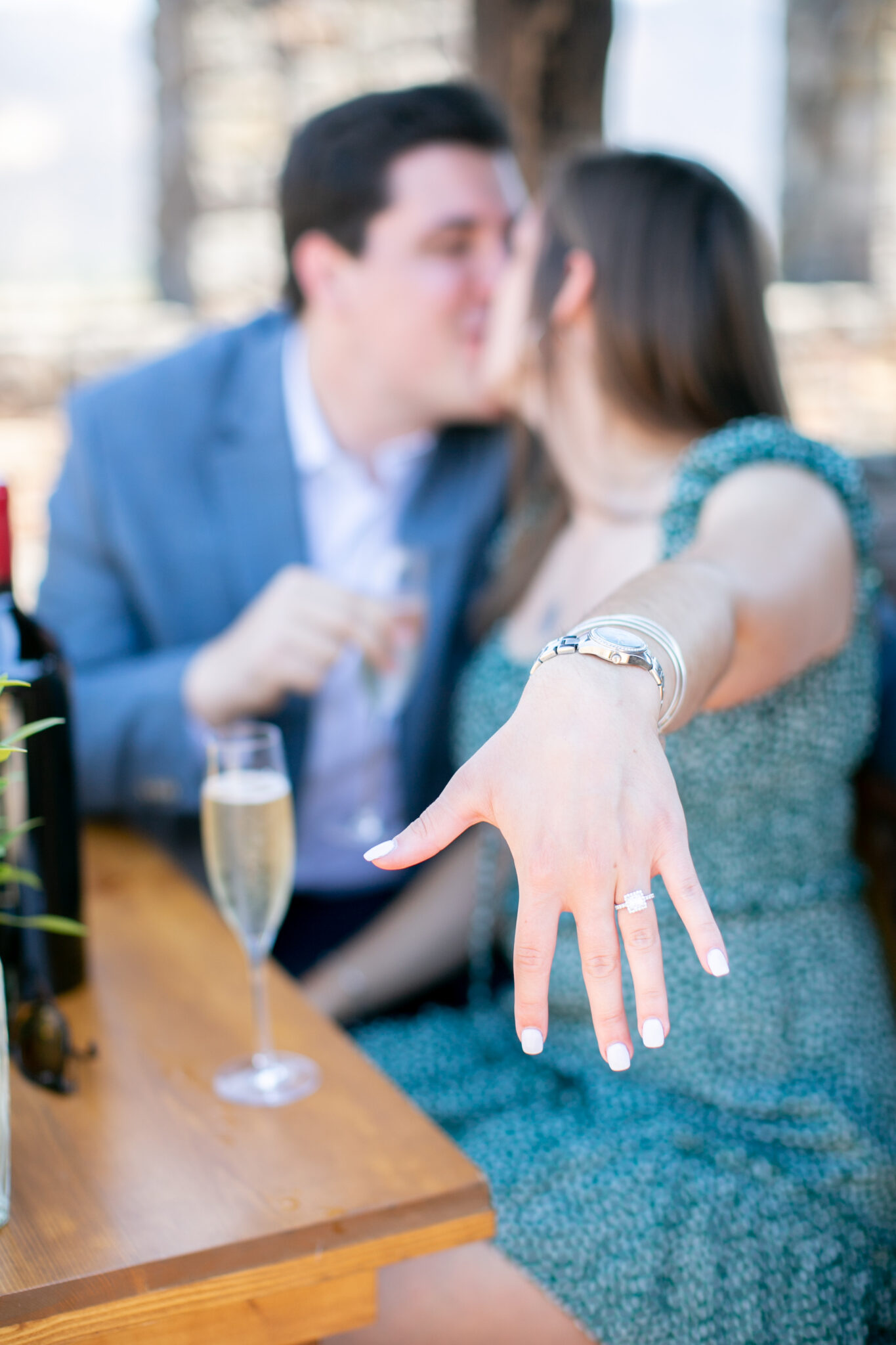 couple celebrating engagement with champagne and showing ring