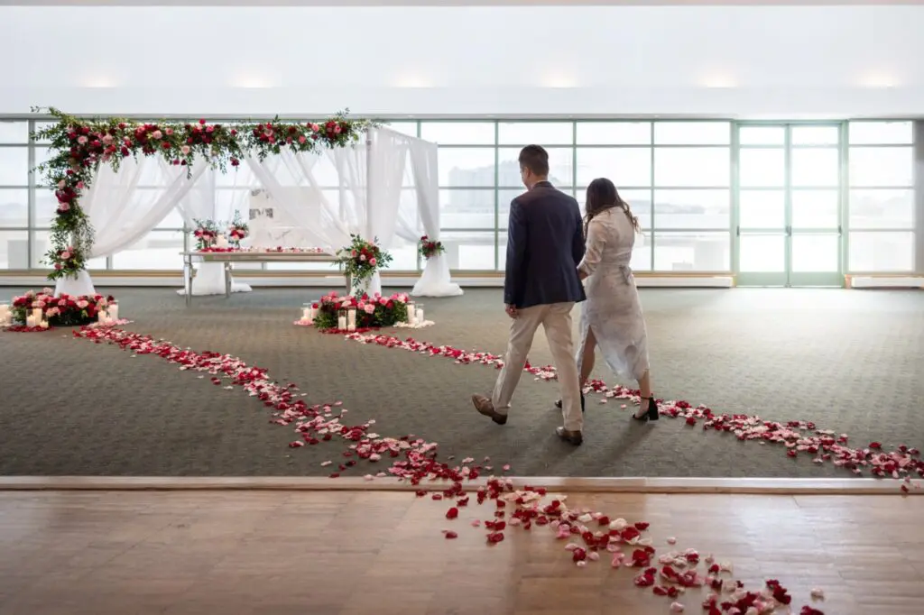 couple walking towards red rose backdrop