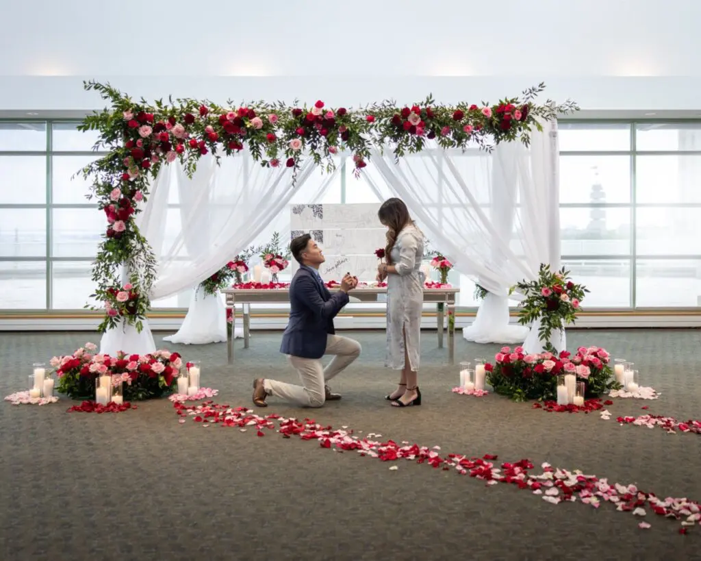 man down on one knee in front of red rose backdrop