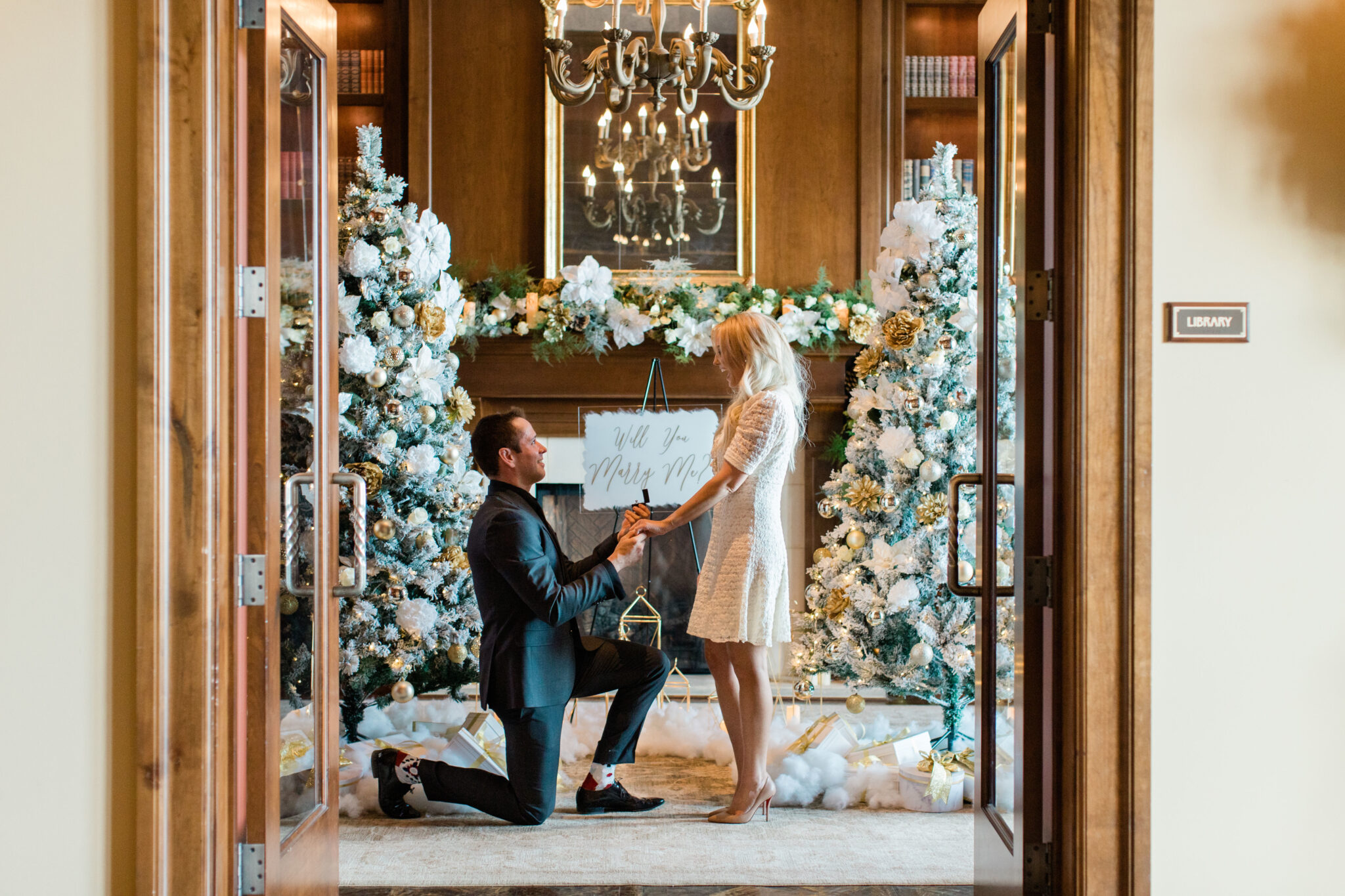 man proposing in front of two christmas trees