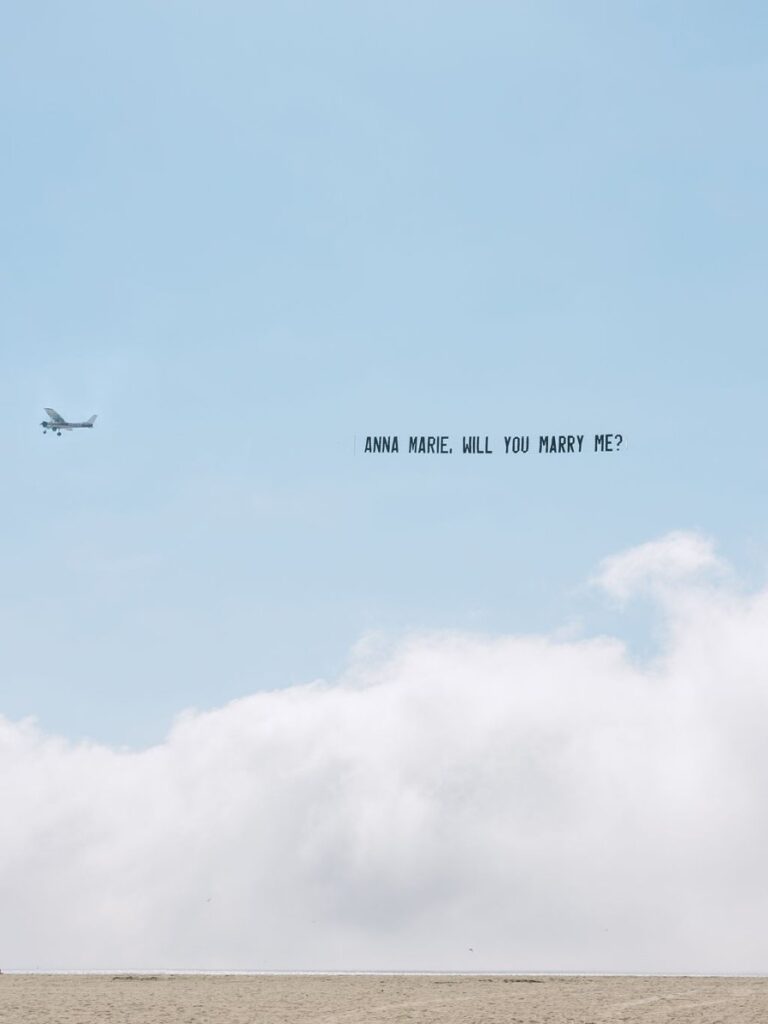 plane flying over ocean with marry me sign