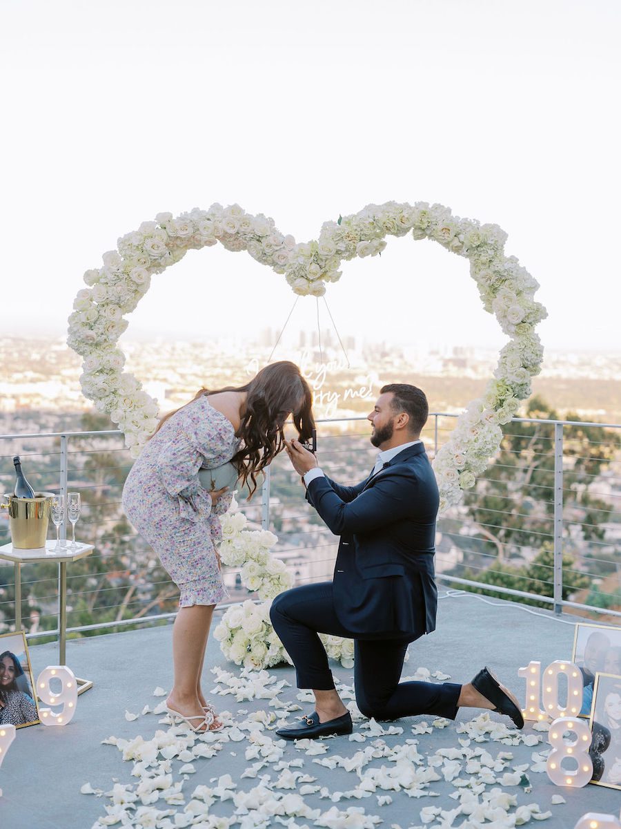 surprise los angeles proposal set up by the yes girls with white heart flower arch