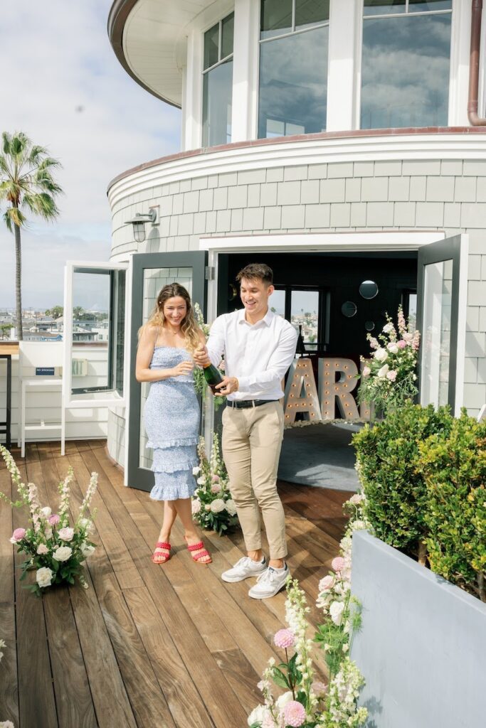 couple celebrating proposal with popping champagne