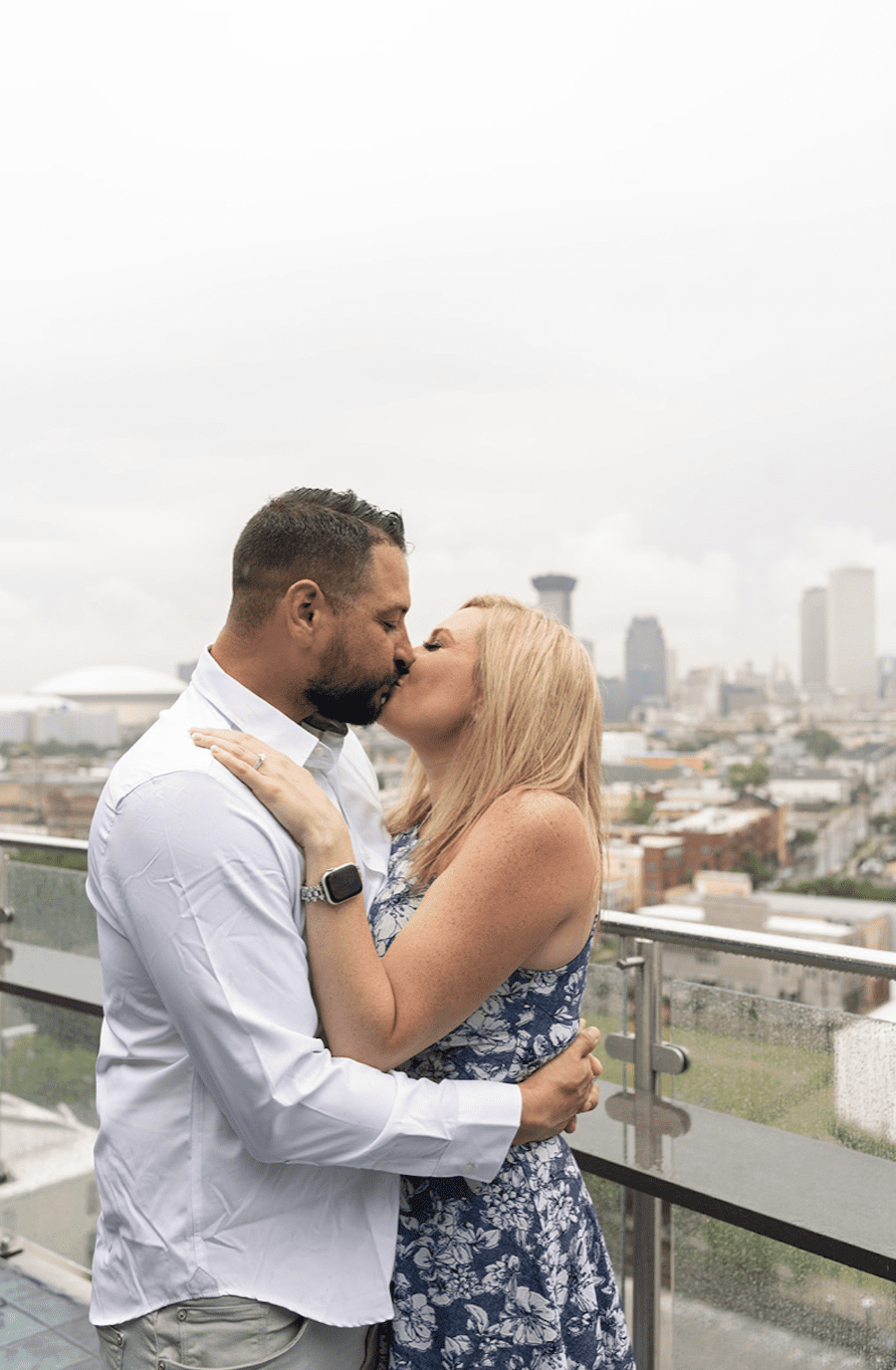Romantic rooftop proposal in new orleans neutral florals. Couple kissing in the rain