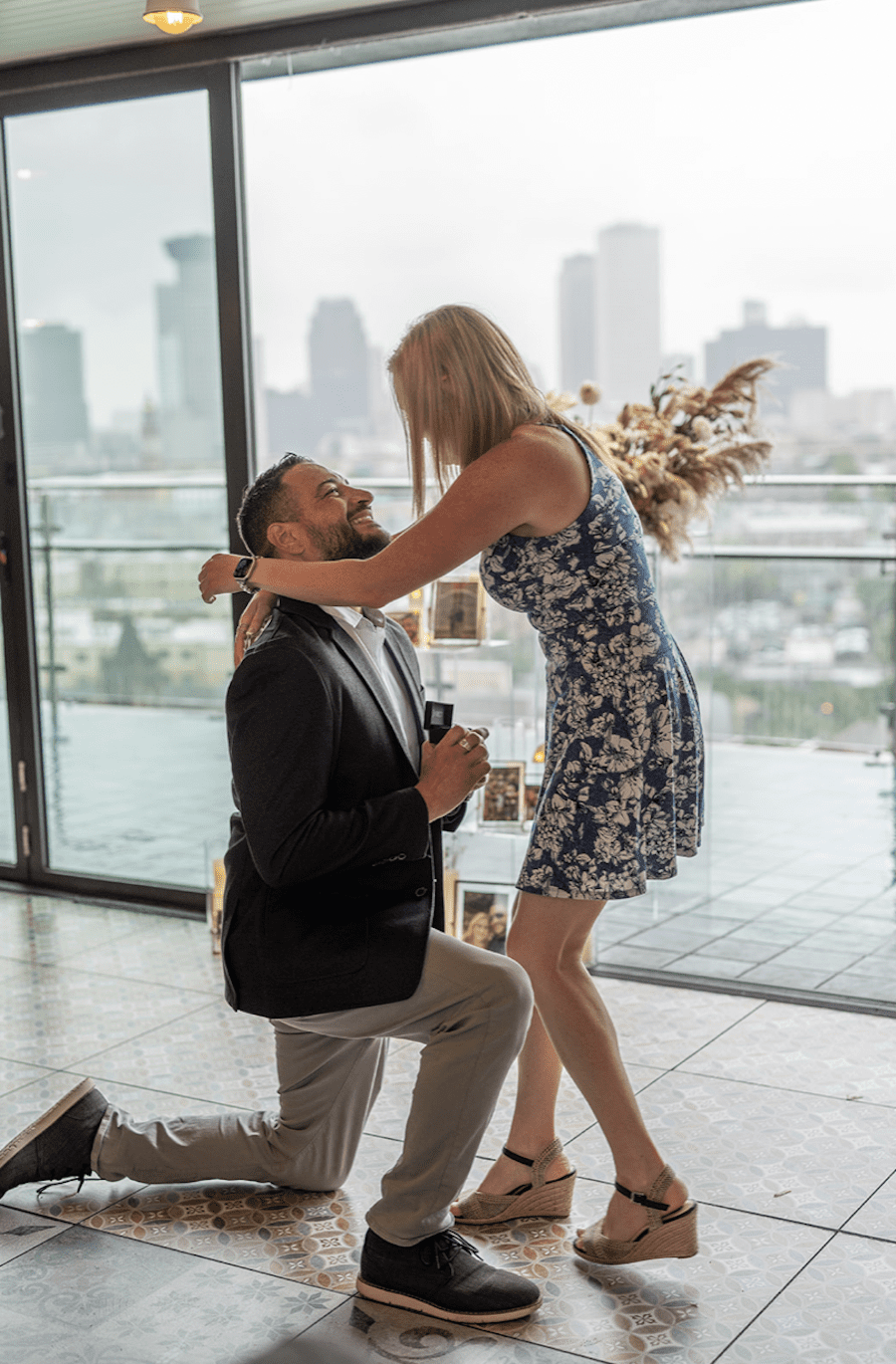 Romantic rooftop proposal in new orleans neutral florals. Down on one knee