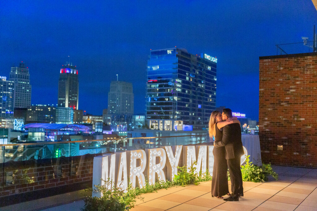 marry me light up marquee letters on a rooftop romantic proposal 