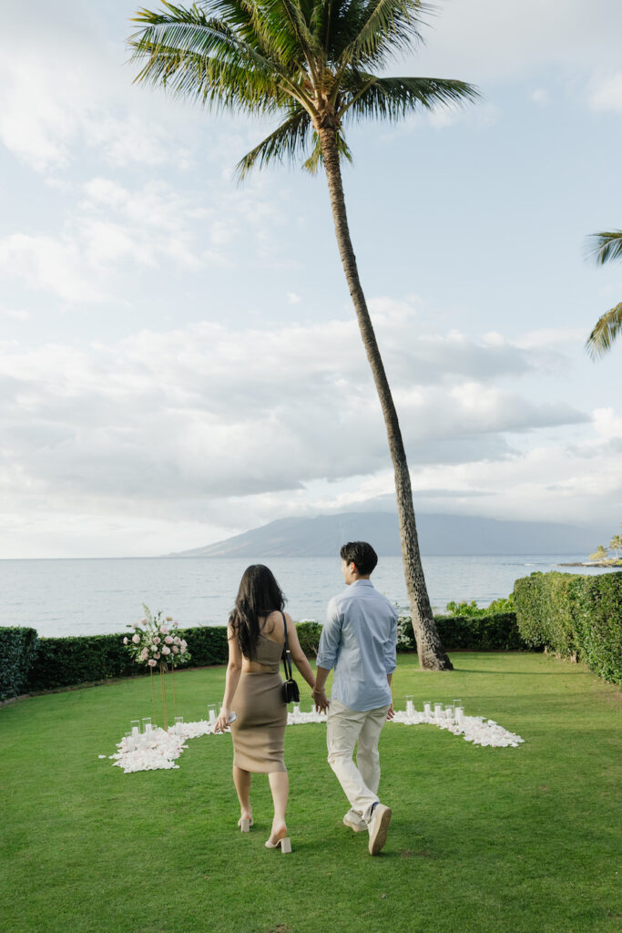 couple holding hands in front of their proposal set up