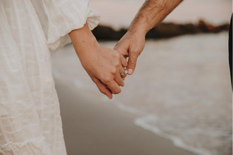 Couple holding hands on the beach during a romantic engagement at sunset in Miami
