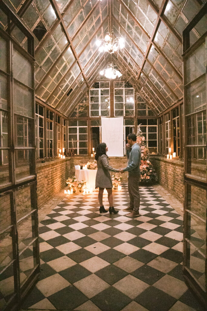 Luxury holiday proposal in Austin glasshouse featuring checkered floors, candles, and florals
