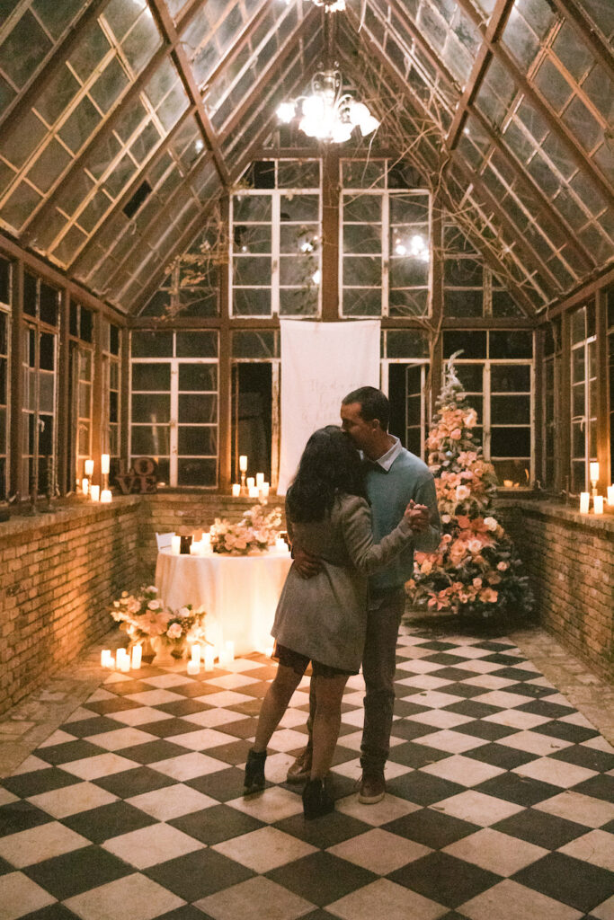 Holiday proposal in Austin TX at the iconic checkered floor glasshouse with candlelight and pink florals
