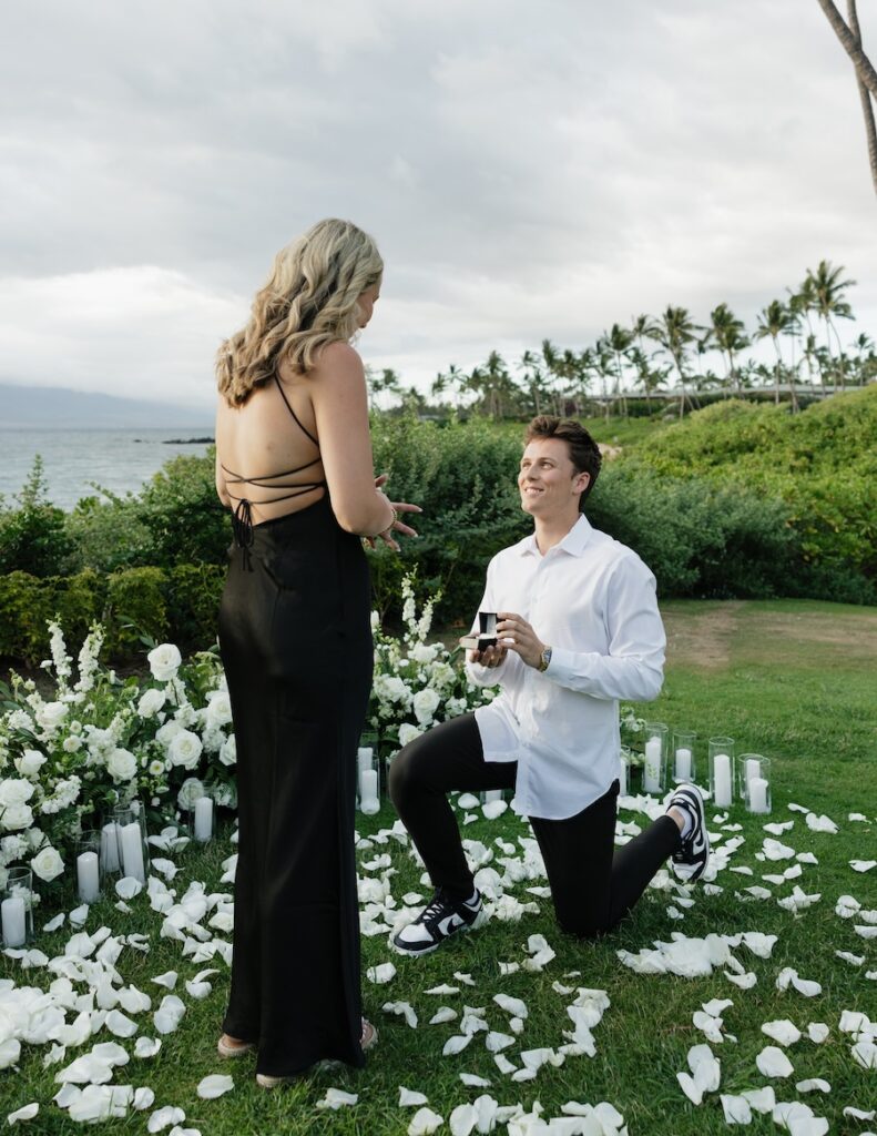 Proposal on one knee in a field of white florals and petals at the Andaz Maui