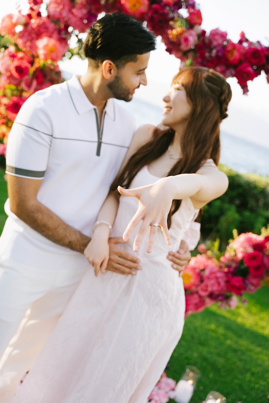 Couple embracing in front of bright pink tropical florals at the Andaz Maui