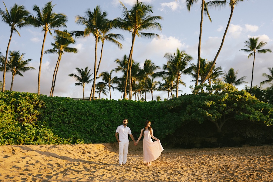 Couple walking toward palm trees on the beach at the Andaz Maui in Wailea