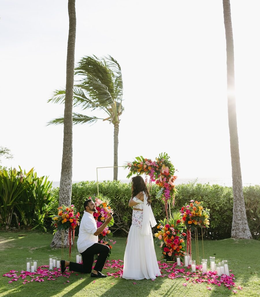 Proposal on one knee under palm trees between pink floral stands at the Andaz Maui