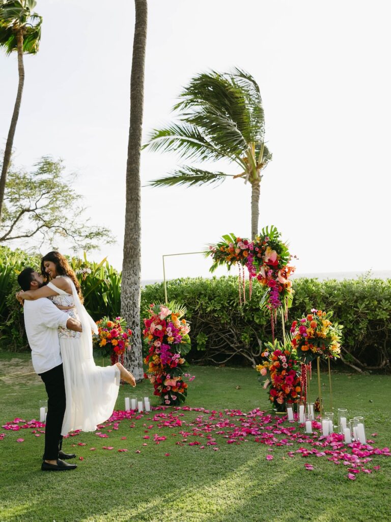 Couple kissing between hot pink and orange floral arrangements at the Andaz Maui