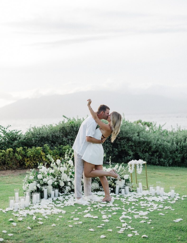 Couple celebrating among white florals on the oceanfront lawn at the Andaz Maui