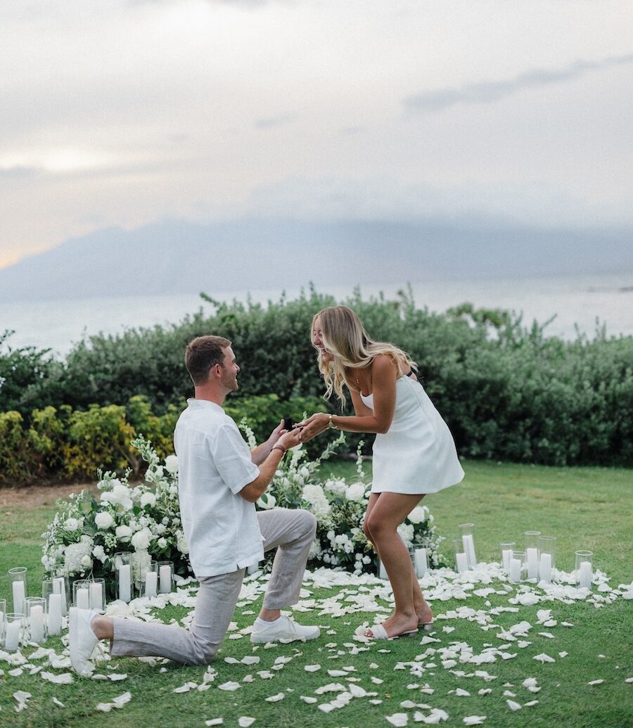 Proposal on one knee among white florals and candles at the Andaz Maui