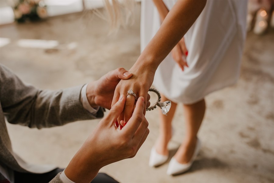 Elegant wedding ring exchange between couple at indoor proposal, themed like a giant, life-sized advent calendar themed proposal