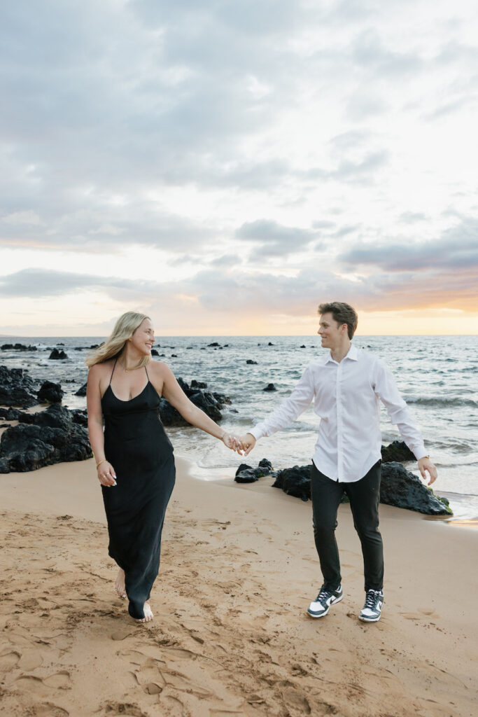Romantic couple holding hands on the beach during sunset.