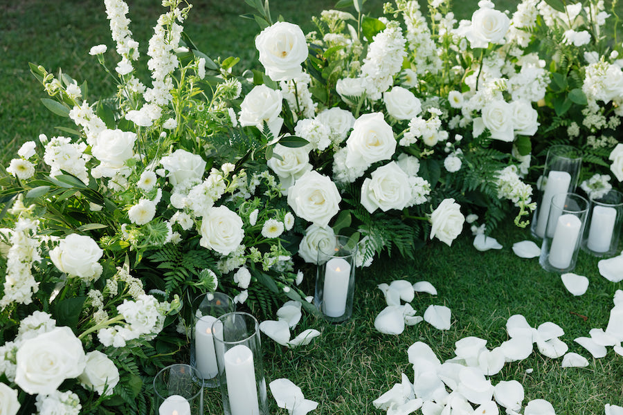 Elegant white floral arrangement with candles for proposal decor.