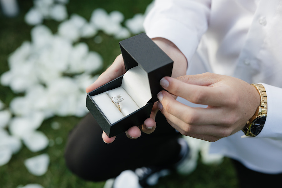 Wedding ring box held by groom during outdoor ceremony.