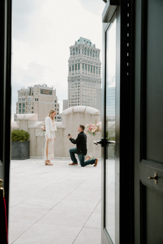 Romantic proposal scene on a rooftop with a city skyline backdrop, capturing a special moment betwee.