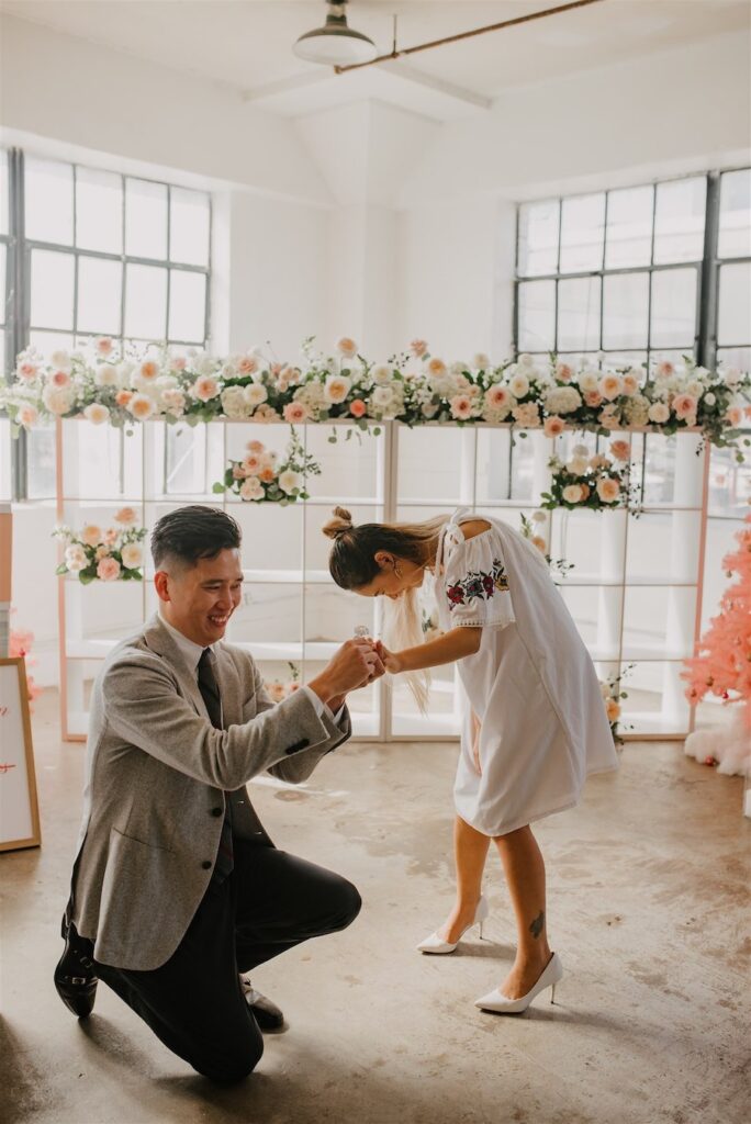 Romantic proposal scene with couple at The Yes Girls venue, surrounded by elegant floral decor and n.