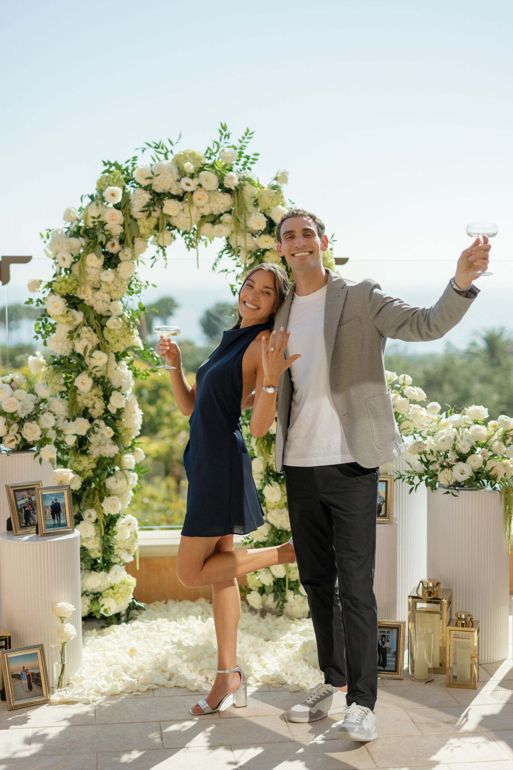 Engaged couple posing in front of the floral arch with ocean views in Newport Beach
