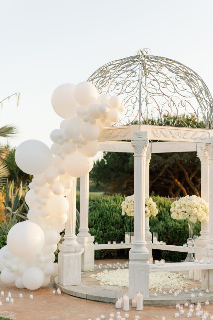 Ivory balloon garland wrapping a white wrought-iron gazebo for an Orange County proposal