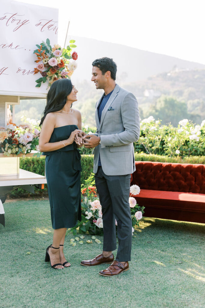 Man holding the ring box as she reacts in the garden