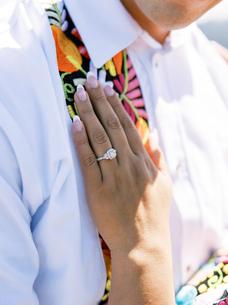 Close-up of her engagement ring against embroidered fabric