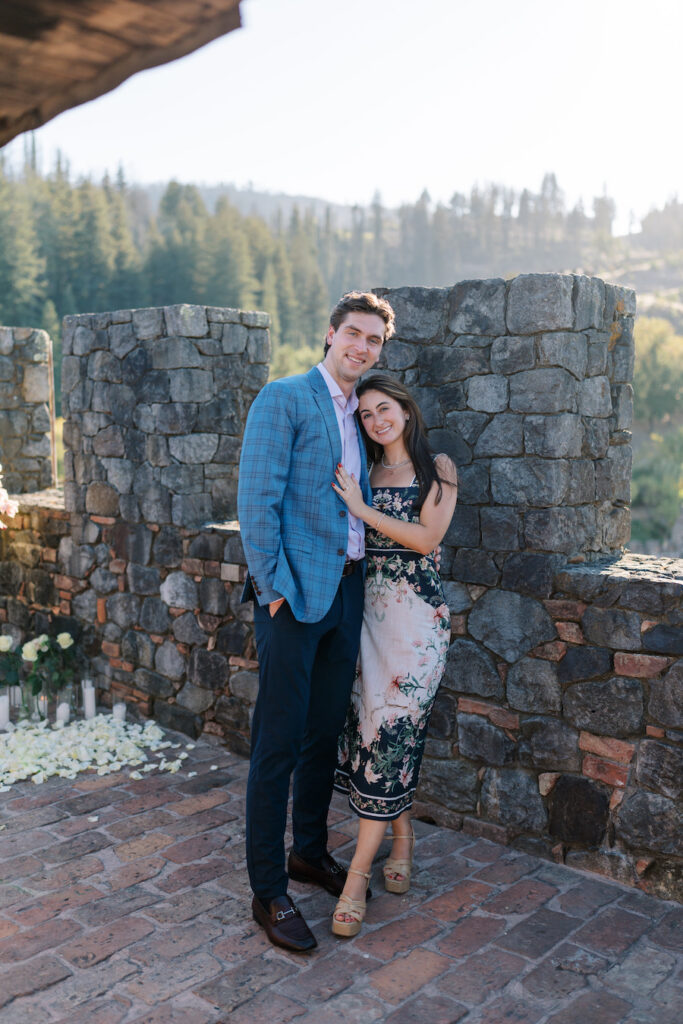 Newly engaged couple posing against the castle stone wall