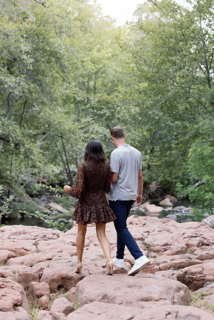 Couple walking hand in hand toward the red rock creek
