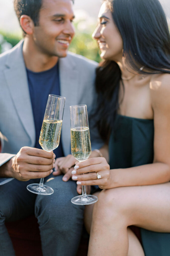 Close-up of champagne glasses and her engagement ring
