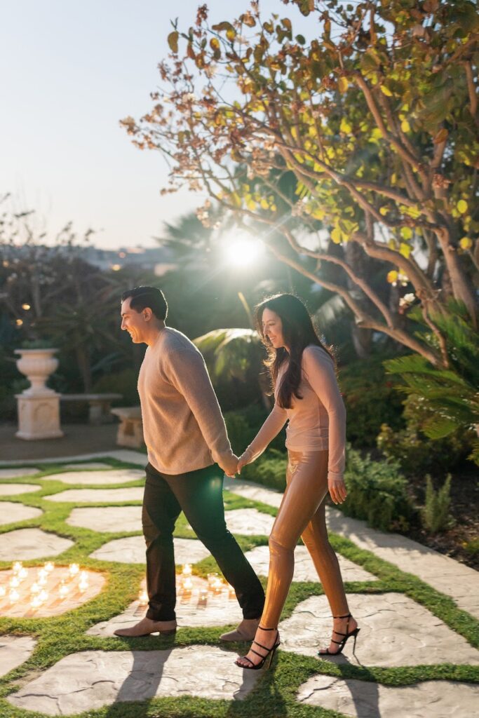 Couple walking hand in hand through the garden toward their gazebo proposal