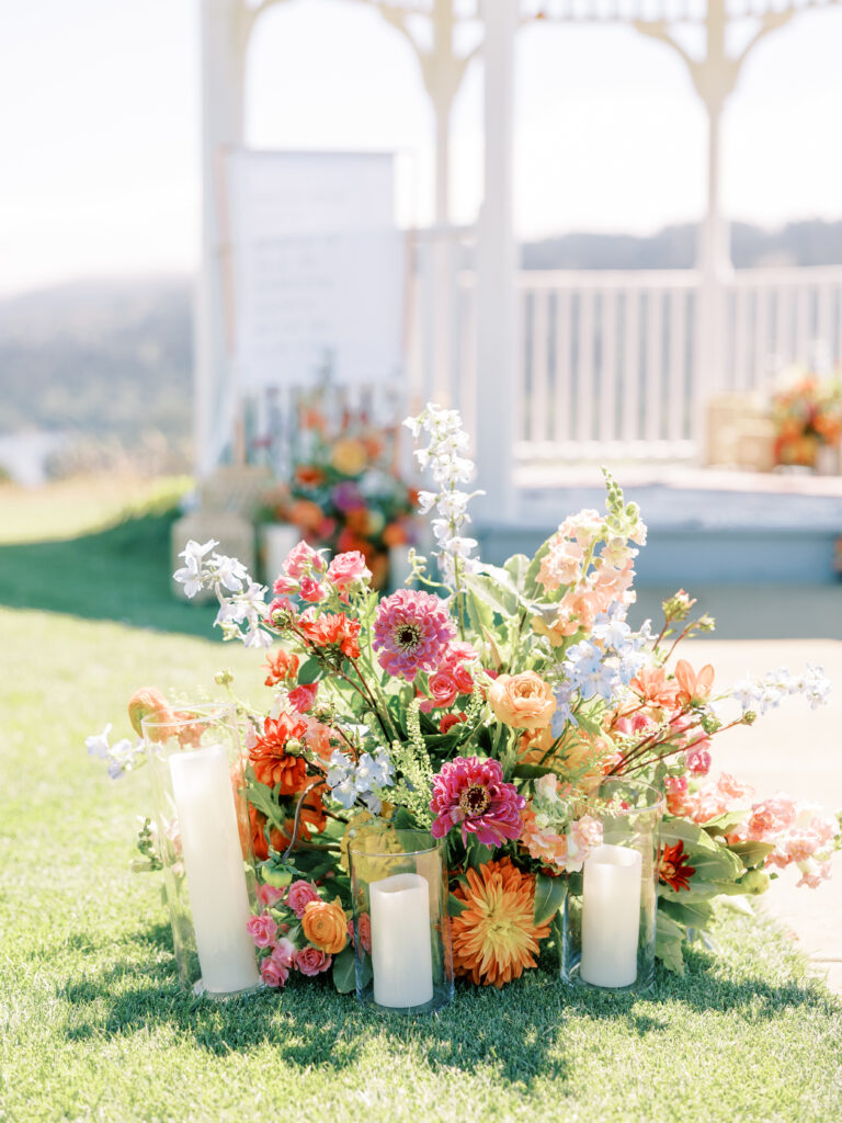 Bright orange, pink and red florals with candles at the gazebo