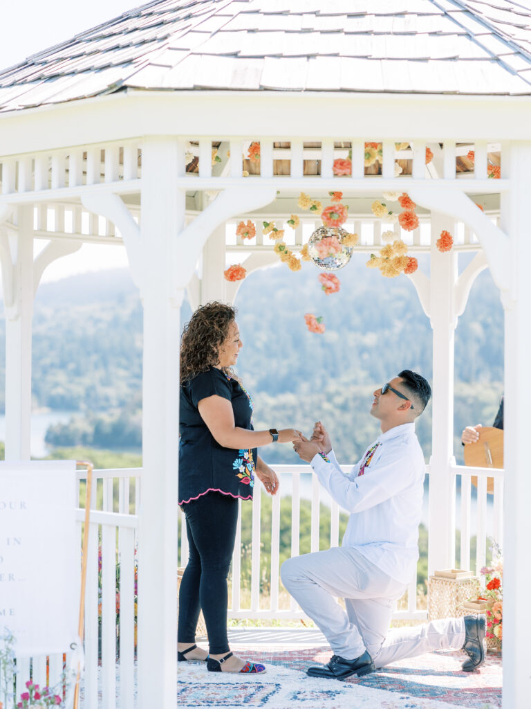 Man on one knee at a Bay Area mariachi proposal inside a white gazebo