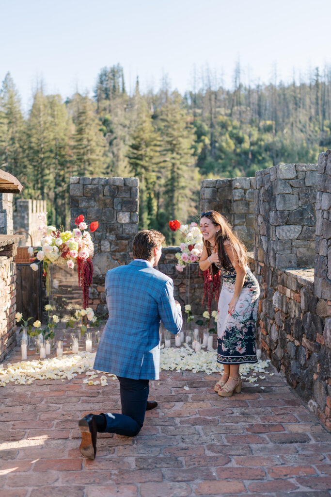 Man on one knee at a Napa vineyard castle proposal on the stone terrace