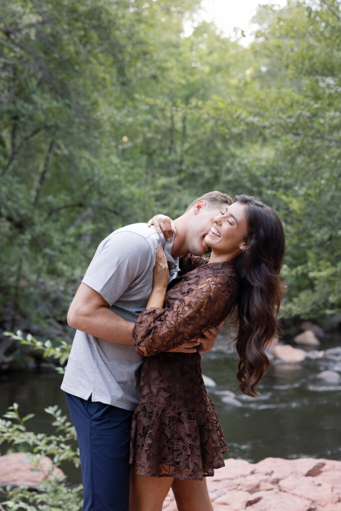 Beck lifts Elle into a hug by the creek after she said yes