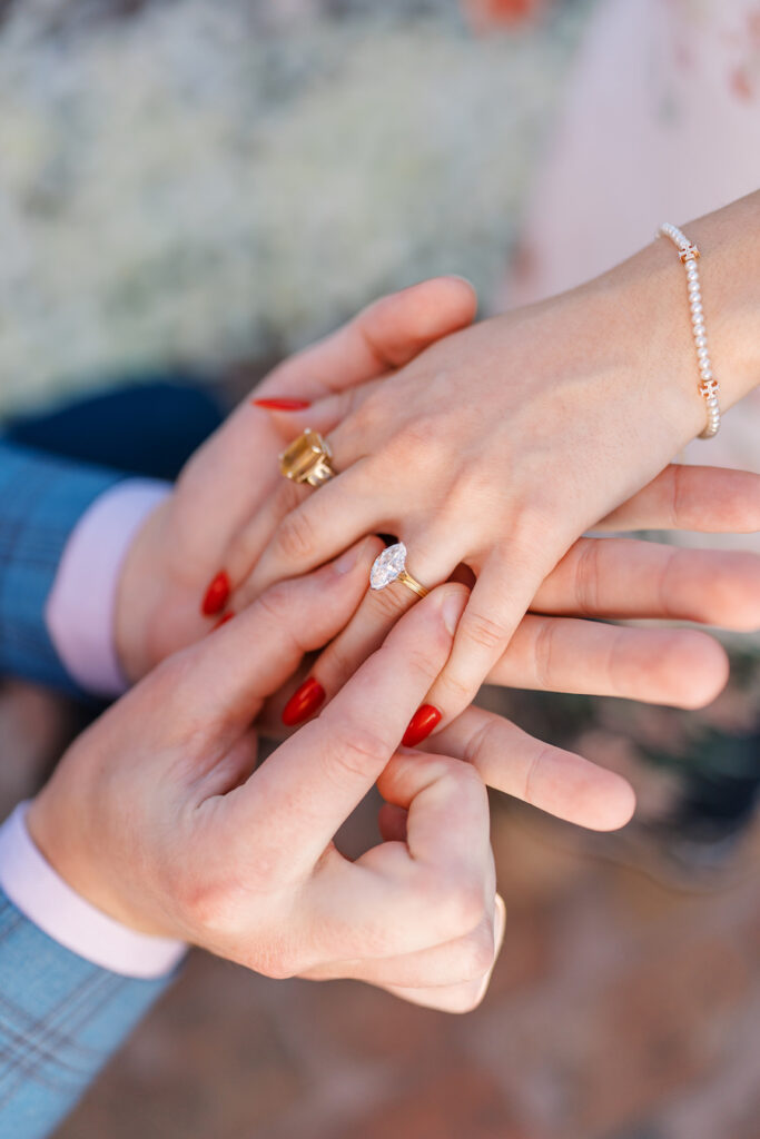 Close-up of him slipping the engagement ring onto her finger