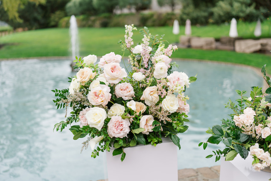 Blush and ivory roses on a white pedestal at the proposal