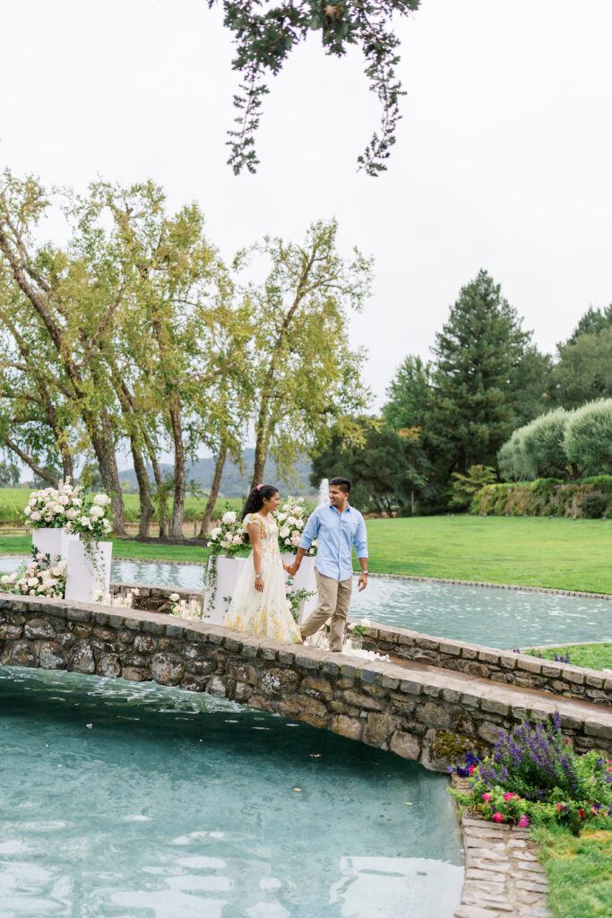 Stone bridge decorated with blush florals over a garden pond