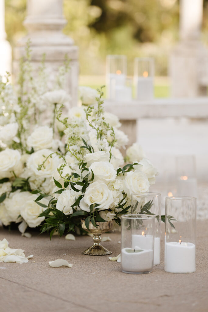White rose and hydrangea arrangements with glass candles beside the gazebo
