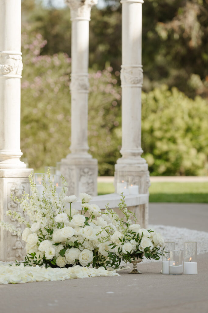 White florals and candles at the base of the gazebo columns